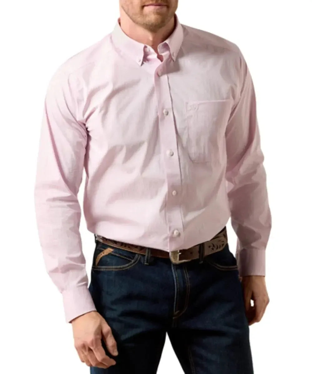 A man wearing a light pink long-sleeve button-down shirt tucked into dark blue jeans with a brown belt, shown from the chin down against a plain white background.