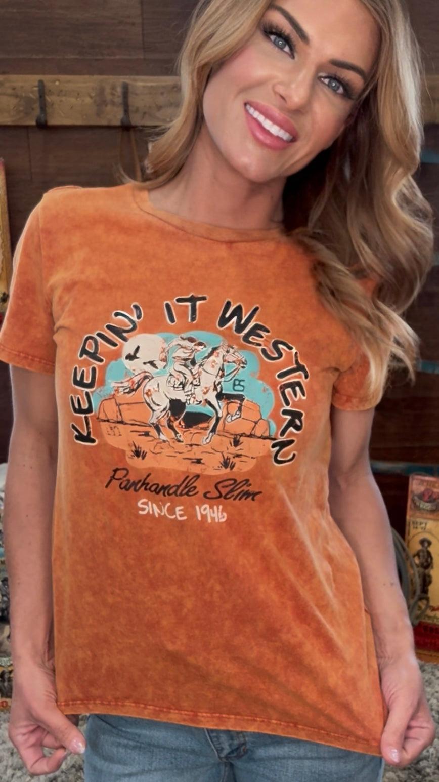 Woman wearing a rust-colored t-shirt with 'Keepin' It Western' graphic design.