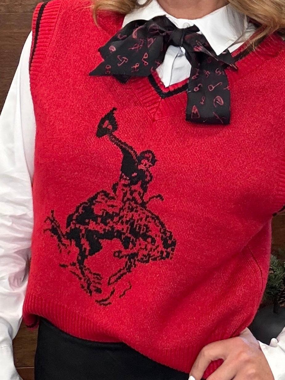 A red knit sweater vest worn over a white collared shirt, featuring a large black cowboy riding a bucking horse graphic on the front and a black bow tie with a small red pattern.