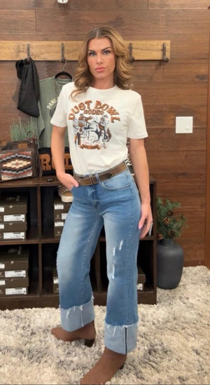 Person wearing blue jeans standing in front of a wooden shelf.