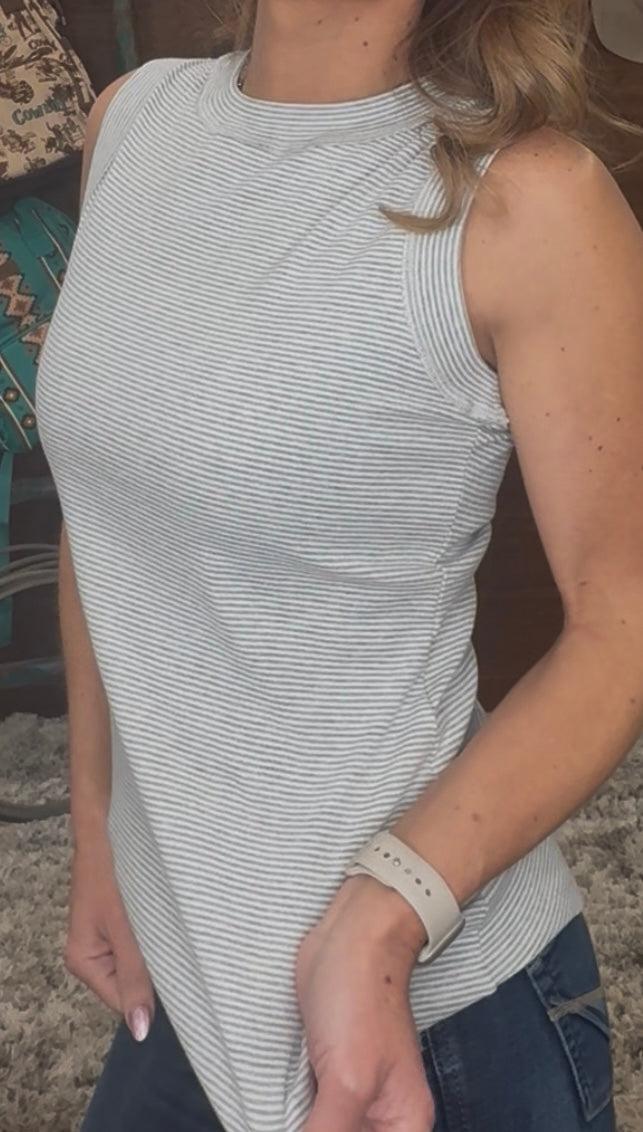 Person wearing a sleeveless striped top with a blurred background