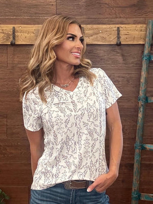 Woman wearing a white floral blouse against a wooden background