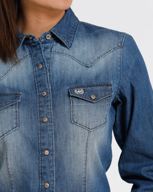 Close-up of a blue denim shirt with a brand logo on a white background