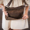 Brown leather bag with a visible brand logo worn by a person.