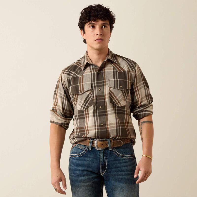 A man wearing a green and beige plaid button-down shirt