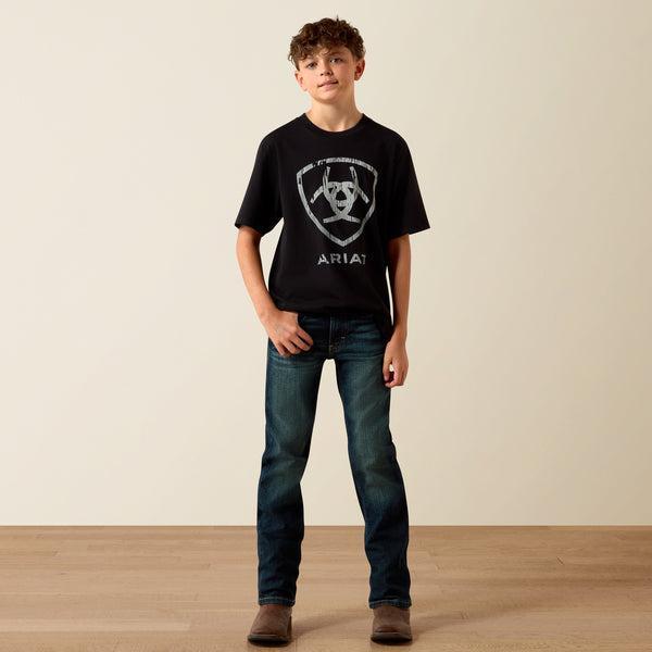Person wearing a black t-shirt with a logo and text, standing against a plain background