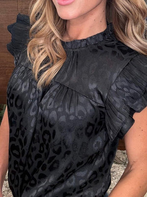 Black leopard print top worn by a person with blurred background