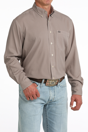 Man wearing a patterned beige shirt and light blue jeans on a white background