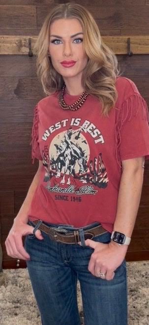 Woman wearing a red graphic t-shirt with text and graphics, standing against a wooden wall.