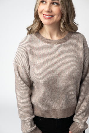 Woman wearing a beige sweater against a white background