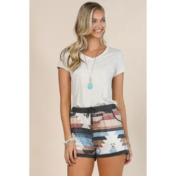 Woman wearing a white t-shirt and patterned shorts on a beige background