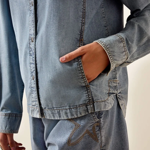 Woman wearing a denim shirt against a beige background