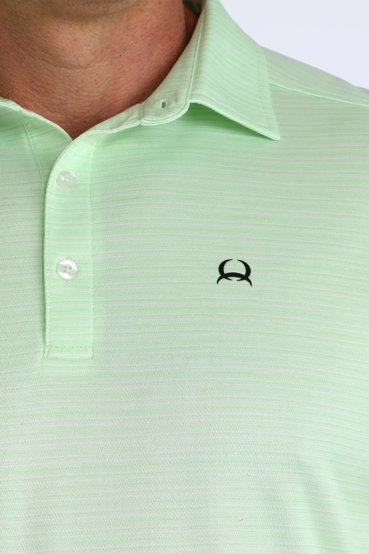 Close-up of a light green polo shirt with a small logo on the chest.