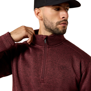 Man wearing a maroon half-zip sweatshirt with a logo on a white background