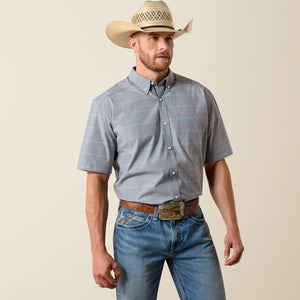 Man wearing a plaid shirt, jeans, and a cowboy hat on a beige background