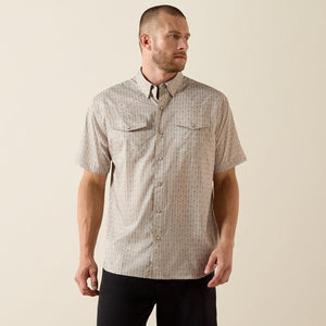 Man wearing a short-sleeve button-up shirt with a subtle pattern on a beige background