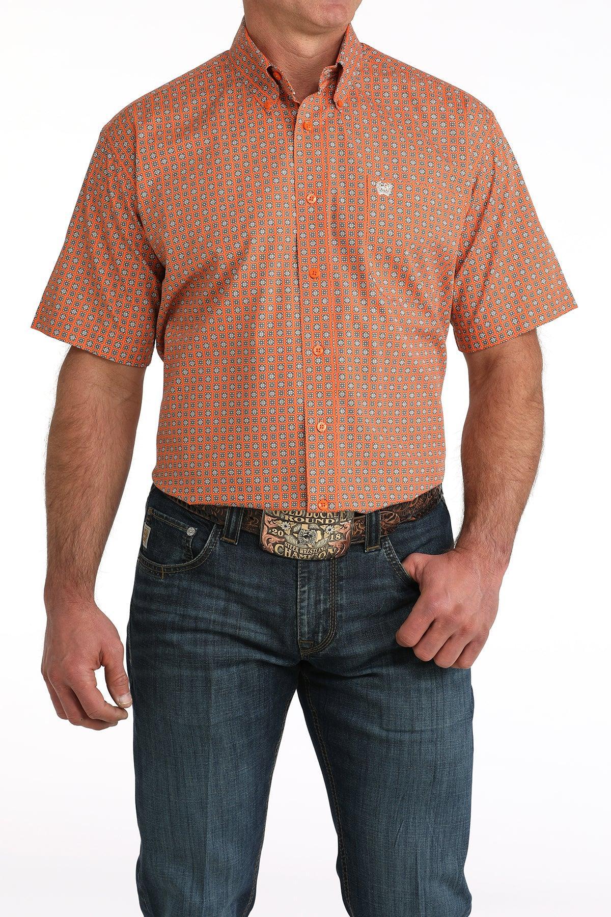 Man wearing an orange patterned shirt and blue jeans on a white background