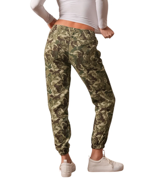 A person shown from the back wearing camouflage jogger pants with an elastic waist and cuffs, paired with a white long-sleeve top and white sneakers, on a plain white background.