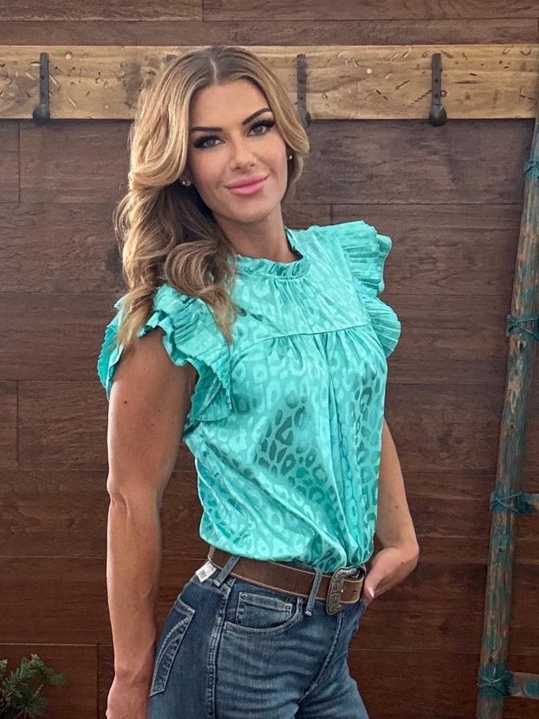 Woman wearing a turquoise top and blue jeans against a wooden background