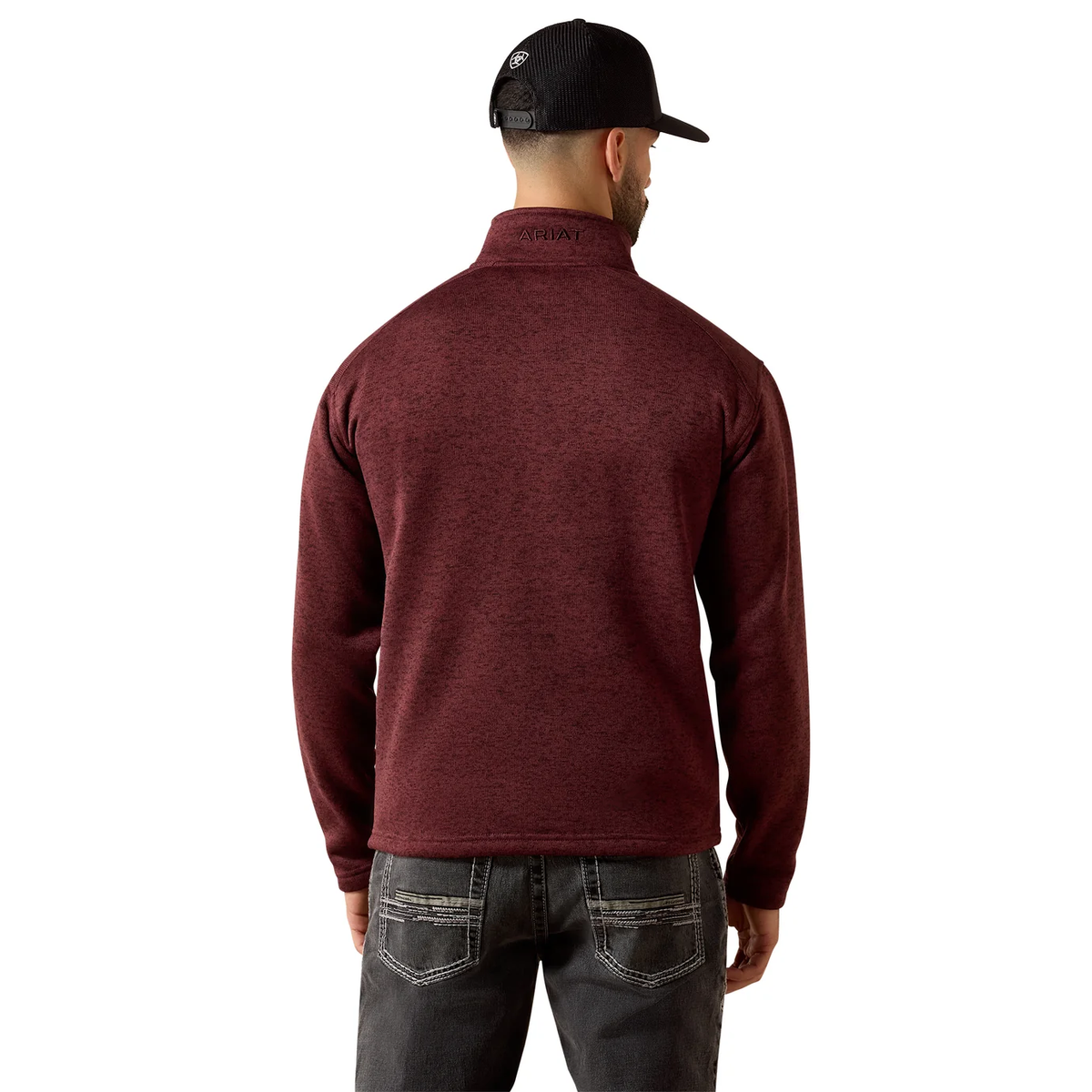 A man viewed from the back wearing a heathered burgundy quarter-zip pullover, dark gray jeans, and a black baseball cap against a plain white background.