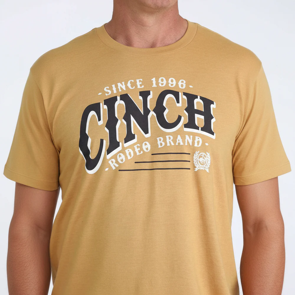 Person wearing a mustard yellow t-shirt with 'Cinch Rodeo Brand' text on a white background