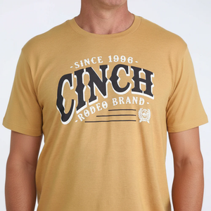 Person wearing a mustard yellow t-shirt with 'Cinch Rodeo Brand' text on a white background