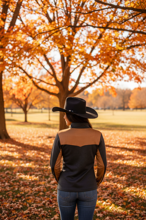 A woman shown from the back wearing a black long-sleeve top with tan color-blocked shoulder and upper back panels.