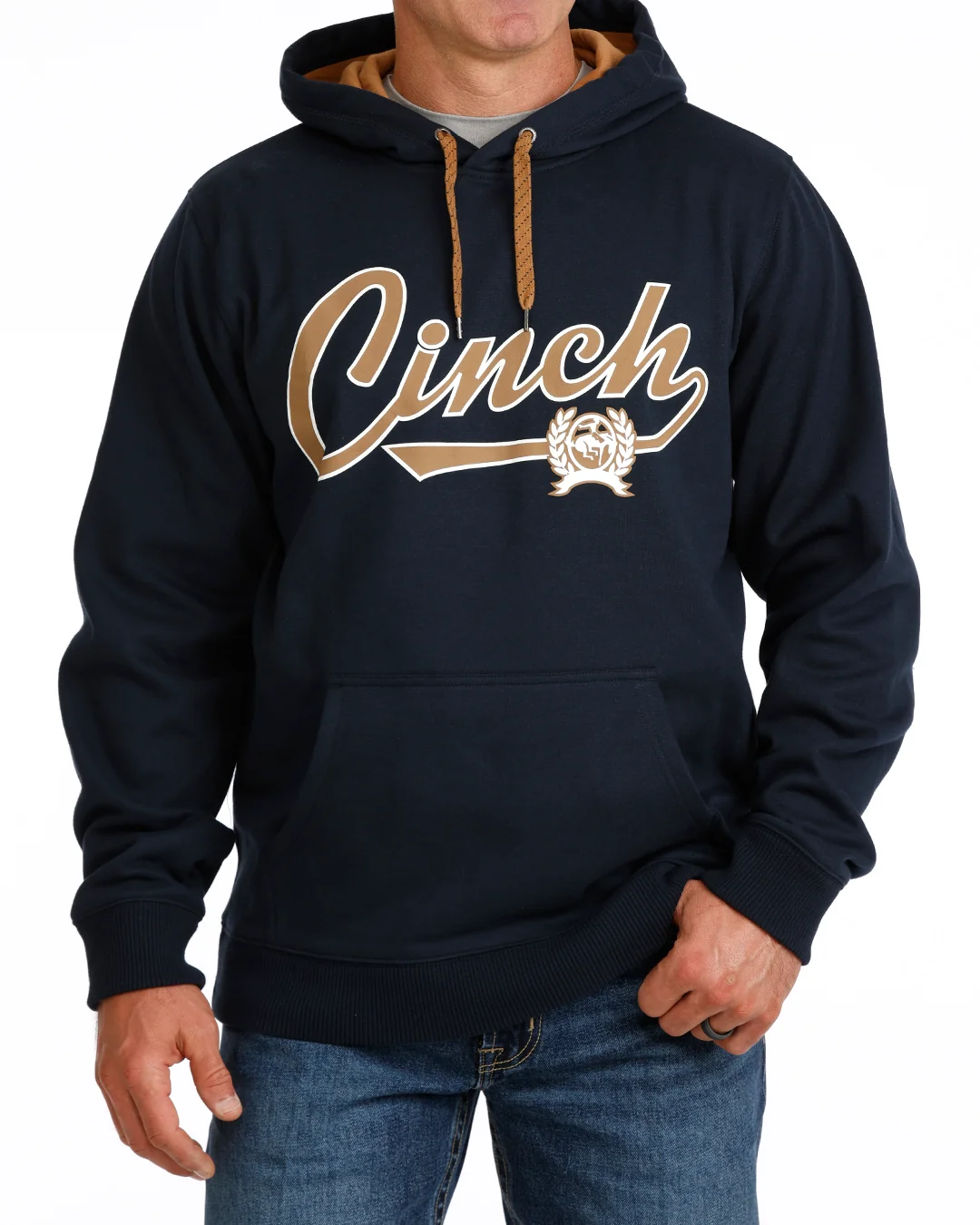 A man wearing a navy blue pullover hoodie with a large tan and white 'Cinch' script graphic across the chest, paired with blue jeans against a plain white background.