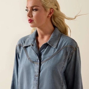 Woman wearing a denim shirt against a beige background
