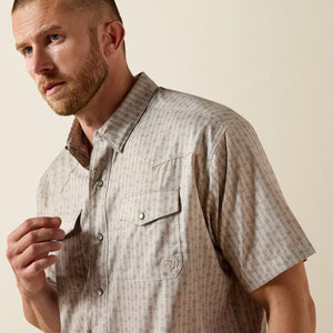 Man wearing a patterned short-sleeve shirt against a beige background