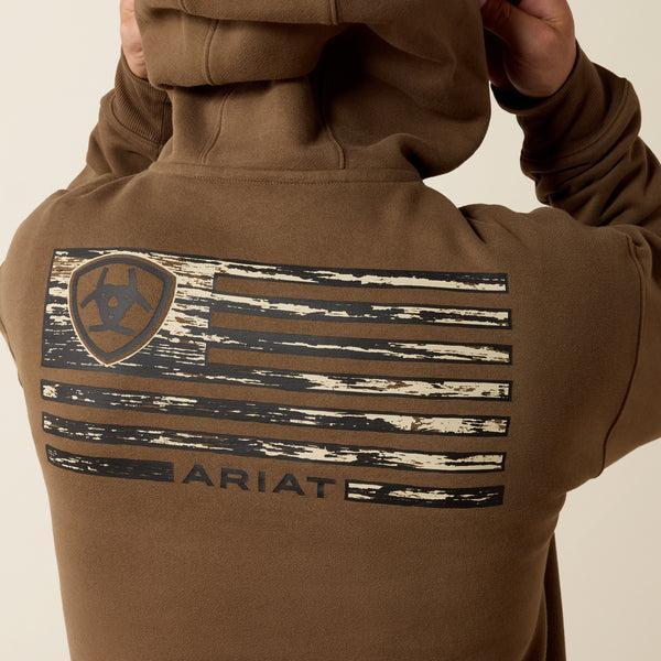 A man viewed from behind wearing a brown hooded sweatshirt with a distressed American flag graphic and the brand name ARIAT on the back.