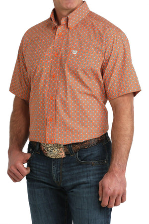 Man wearing an orange patterned shirt and jeans on a white background