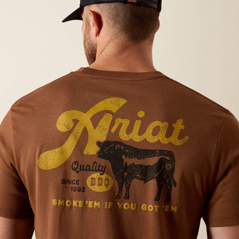 Man wearing a brown Ariat t-shirt with yellow text and a cow graphic on the back.