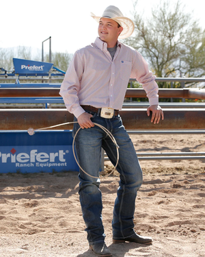Man in cowboy attire holding a lasso in an outdoor setting with 'Friefert Ranch Equipment' branding.