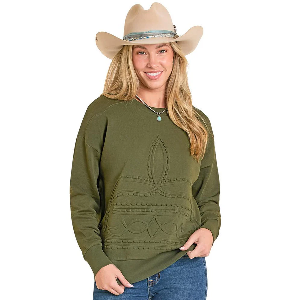 Woman wearing an olive green sweater with a leaf design and a beige cowboy hat on a white background