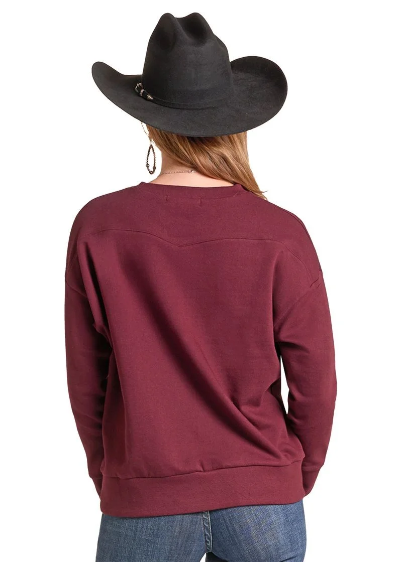 A woman shown from the back wearing a maroon crewneck sweatshirt, blue jeans, and a black cowboy hat against a plain white background.