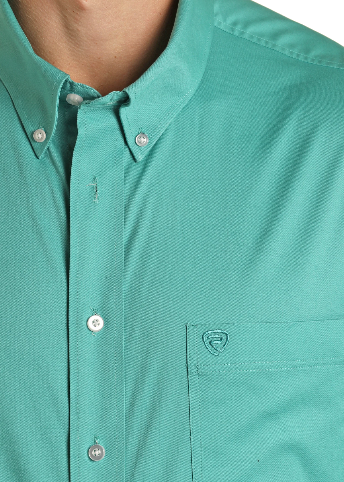 Close-up of a teal button-up shirt with a brand logo on the chest pocket.