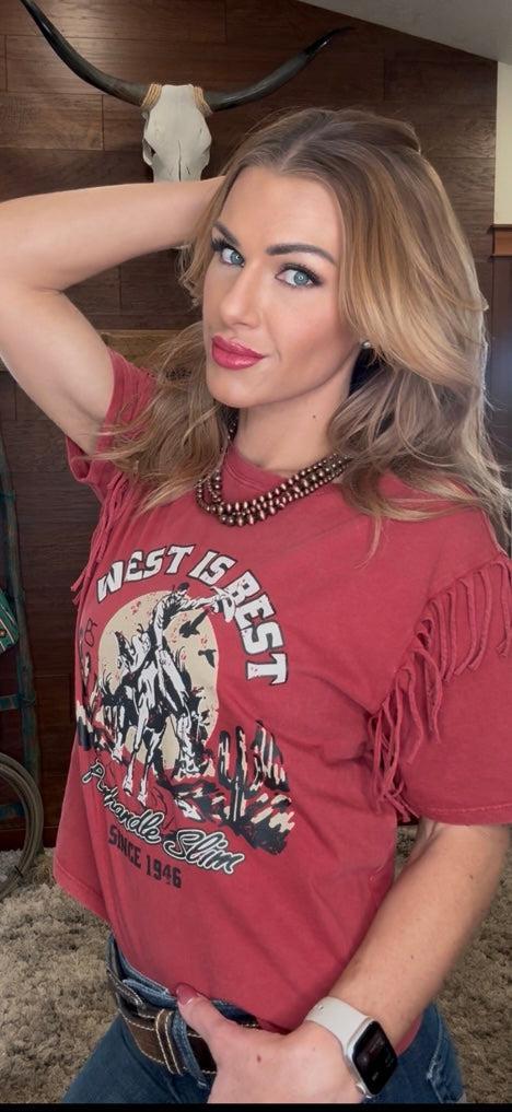 Woman wearing a red fringe shirt with a graphic design, standing indoors.