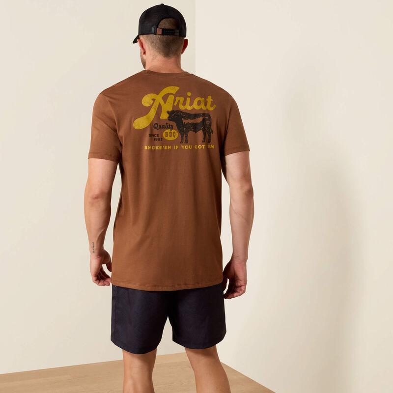 Man wearing a brown Ariat t-shirt with yellow text and a cow graphic on the back.