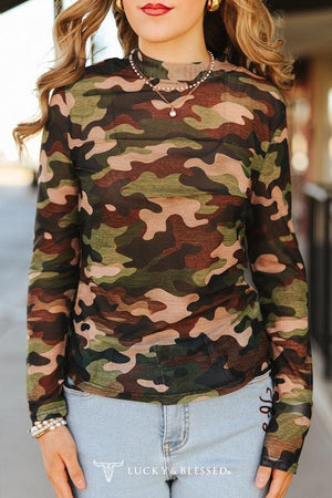 Person wearing a camouflage long-sleeve top with a blurred background