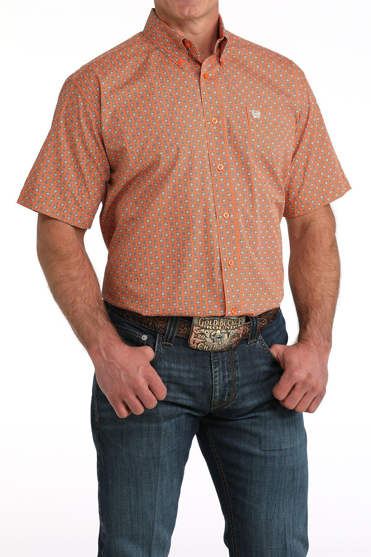 Man wearing an orange patterned shirt and blue jeans on a white background
