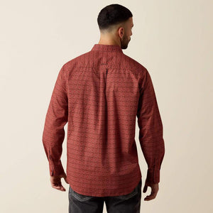 A man viewed from the back wearing a long-sleeve button-up shirt with a textured, geometric pattern in rust red and dark brown, paired with dark jeans against a plain beige background.