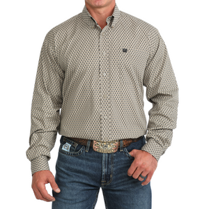 A man wearing a long-sleeve western-style button-down shirt with a small repeating geometric pattern in beige and black, paired with blue jeans and a brown belt.
