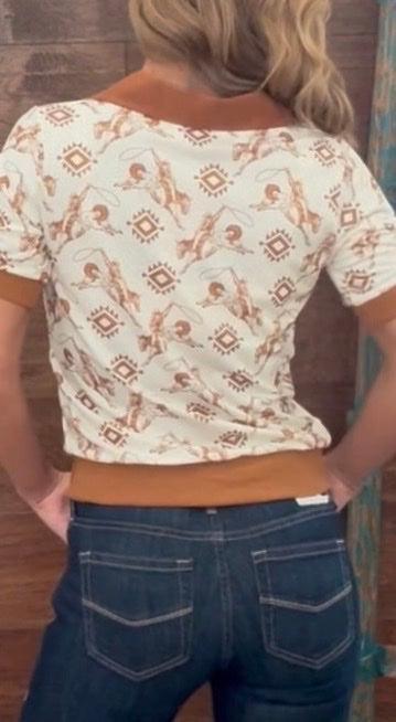 Person wearing a patterned top and jeans with a wooden background