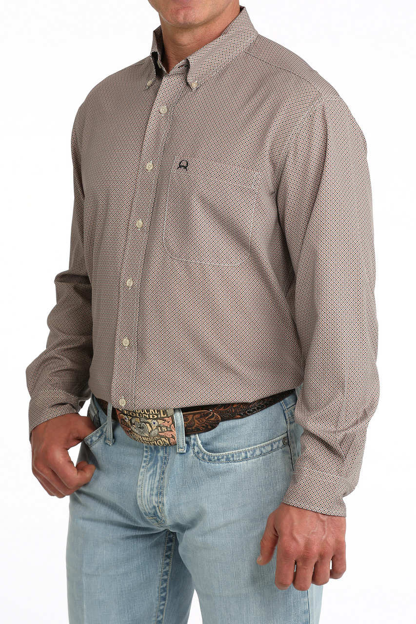 A man wearing a light brown long-sleeve western-style button-down shirt with a subtle micro-pattern, paired with light blue jeans and a brown leather belt with a silver buckle.