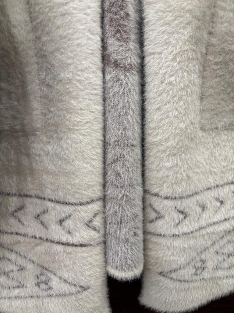 A cream-colored fuzzy knit hooded sweater with a brown horse graphic and geometric patterns. 