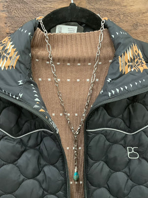 A black quilted zip-front vest with decorative tan and black geometric embroidery on the collar