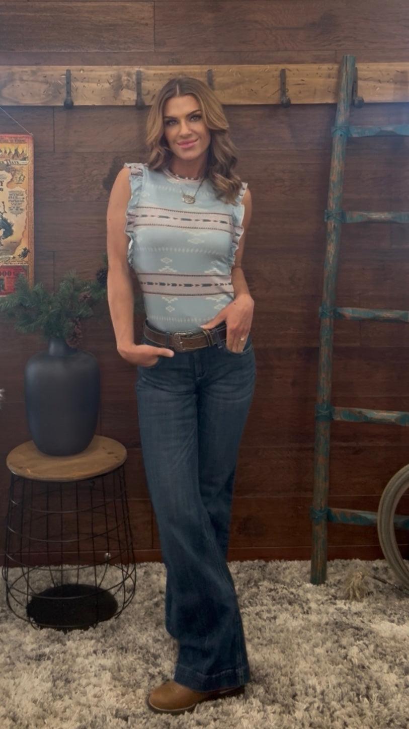 Woman standing in a rustic setting with wooden walls and decor elements.