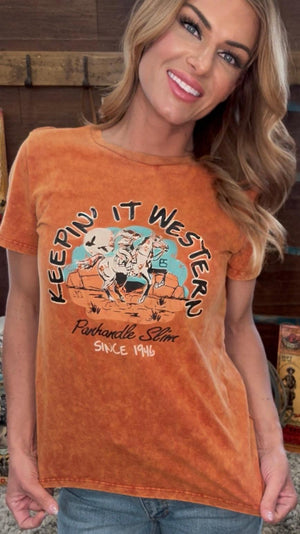 Woman wearing a rust-colored t-shirt with 'Keepin' It Western' graphic design.