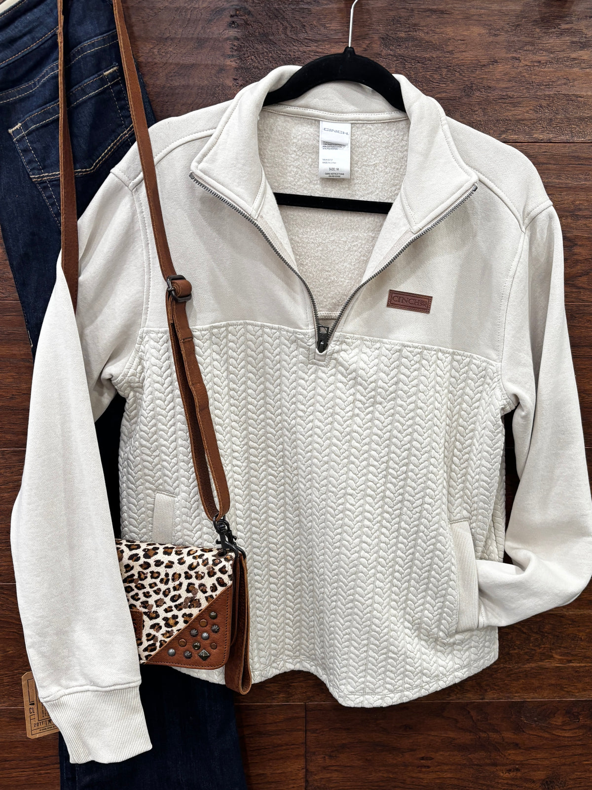 A cream-colored quarter-zip pullover sweater with a textured chevron pattern on the lower half
